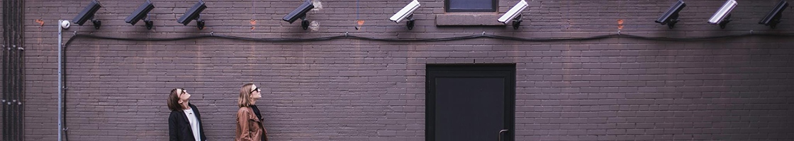 People looking up at security cameras - Policy header (Information Security)