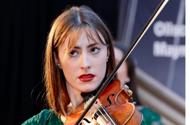 a woman with red hair and brown eyes playing the violin