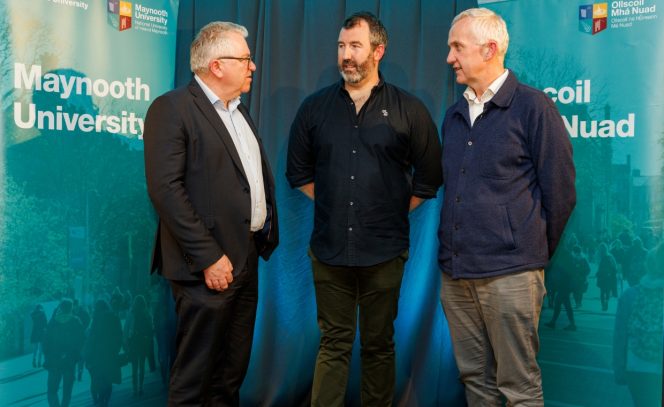 3 men, blue background, left man in a navy suit, white shirt, middle man wearing navy shirt and green trousers and man to the right wearing a navy cardigan 