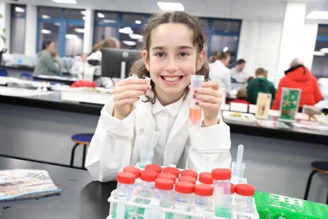 Girls in a white coat holds two test tubes 