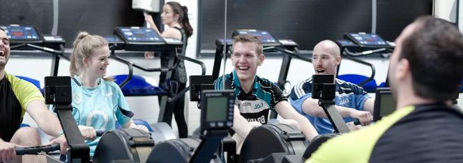 Student Services - Gym - students on rowing machines laughing - Maynooth University