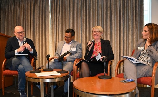 Two men and two women sitting in chairs behind two round tables for a discussion