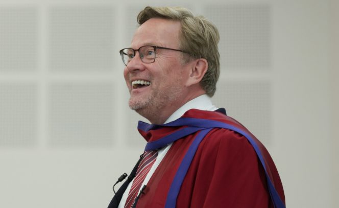 Man looking away from camera smiling, wine robe, glasses