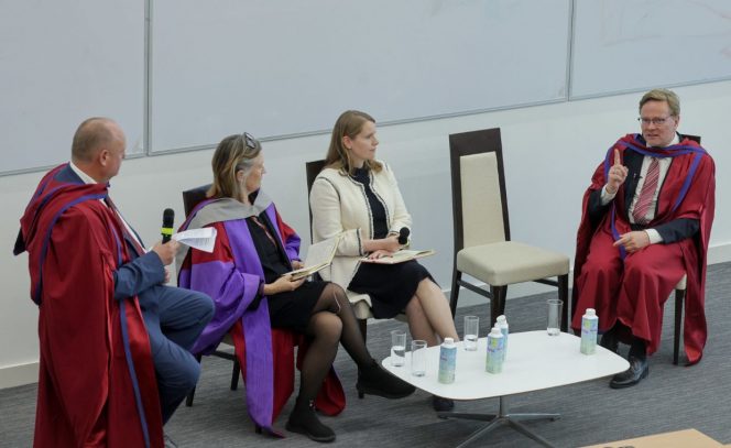 Panel discussion, 2 men and 2 women, wine robes, white jacket, purple robe