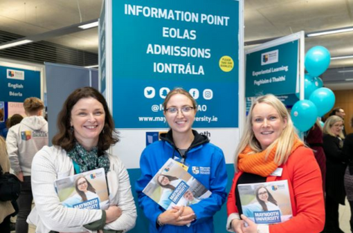 Two Admissions Office staff with a student ambassador holding prospectuses at open day stand