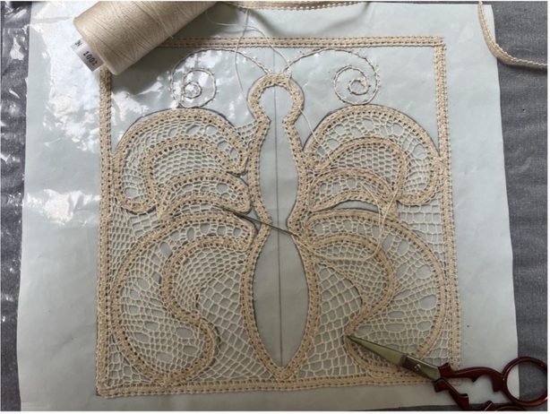 lace, thread and small scissors on white background