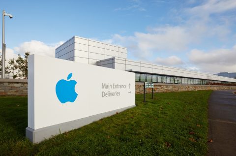 Large building with sign, sign contains a white background and blue Apple logo