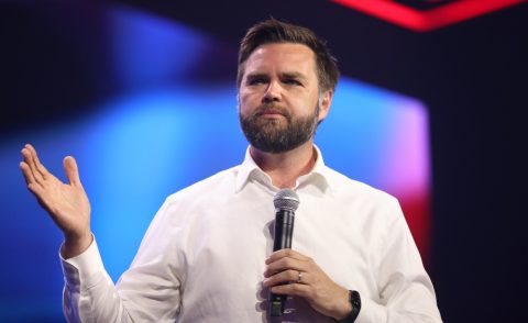 Bearded man holding a microphone in front of a blue background