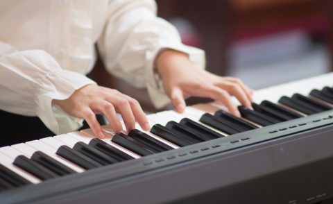 Person wearing a white sleeved shirt playing the piano