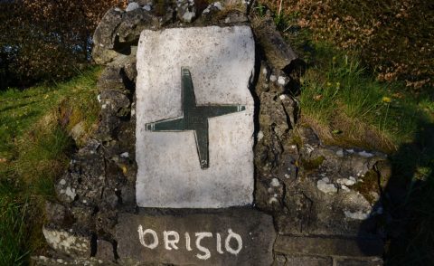 Brigid's Cross carved on stone above a well with words Brigid written under it