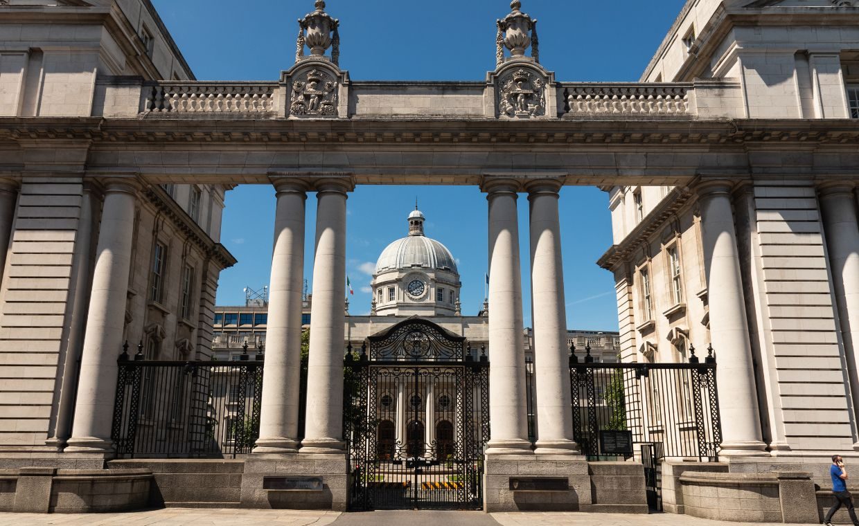 A photo of Dail Eireann shot taken from the Merrion Square side of the complex.  The rotunda is flanked by grey pillars and ornate iron gates