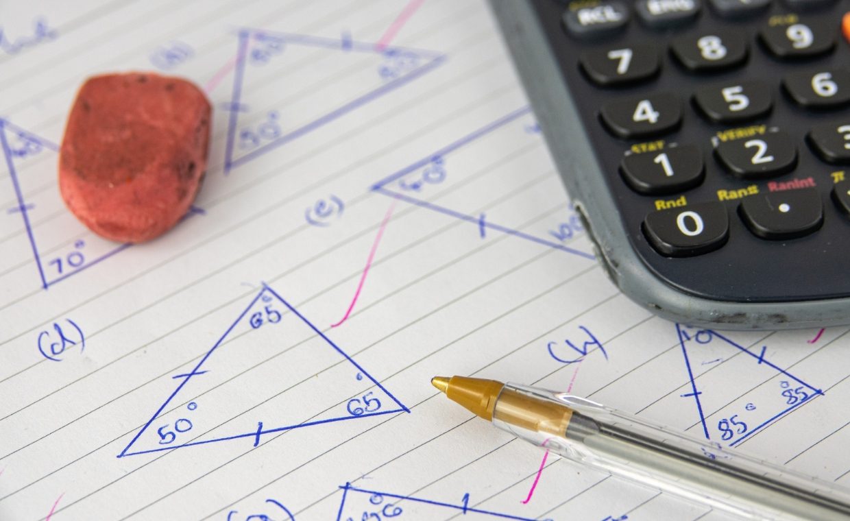 Lined piece of paper with triangles drawn on it and a red rubber, a biro and a calculator sitting on top of it