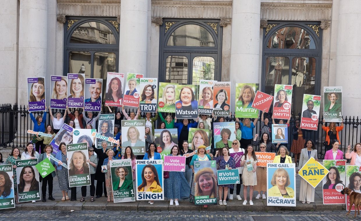 Many women outside Irish government building holding election posters