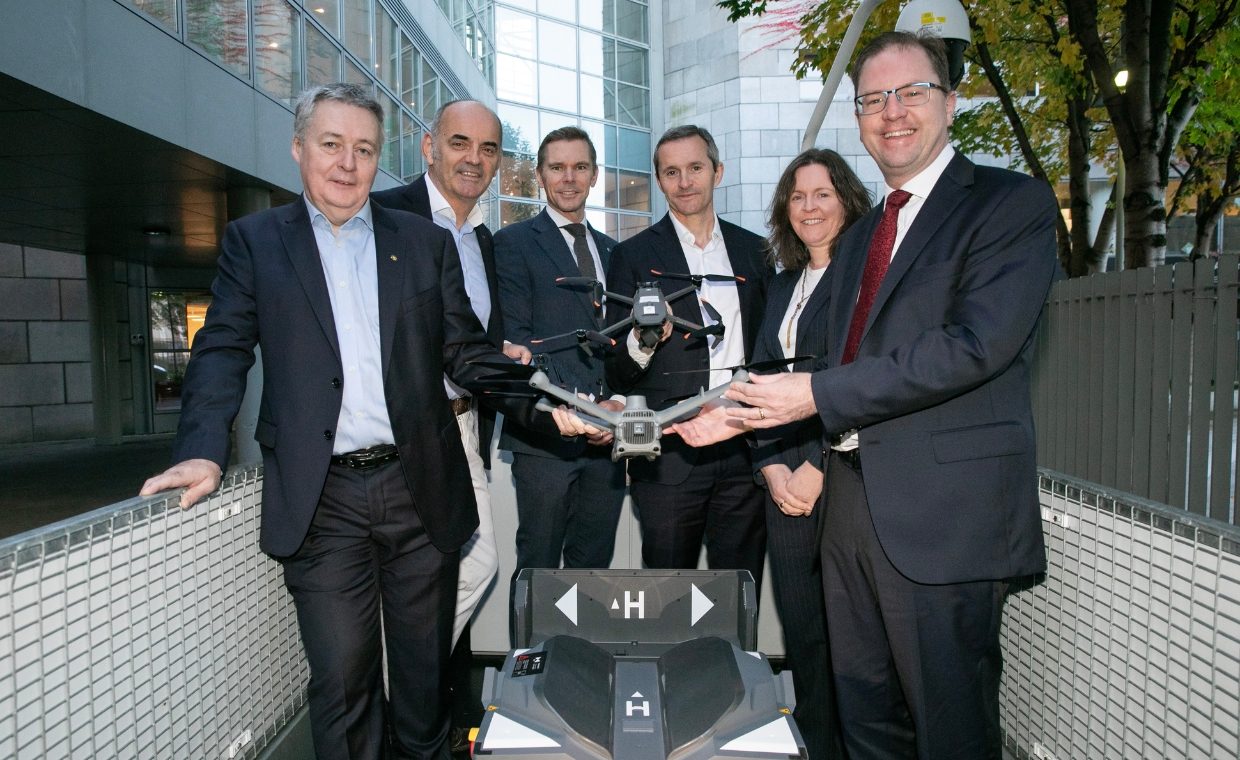 5 man and 1 woman posing for picture holding a drone