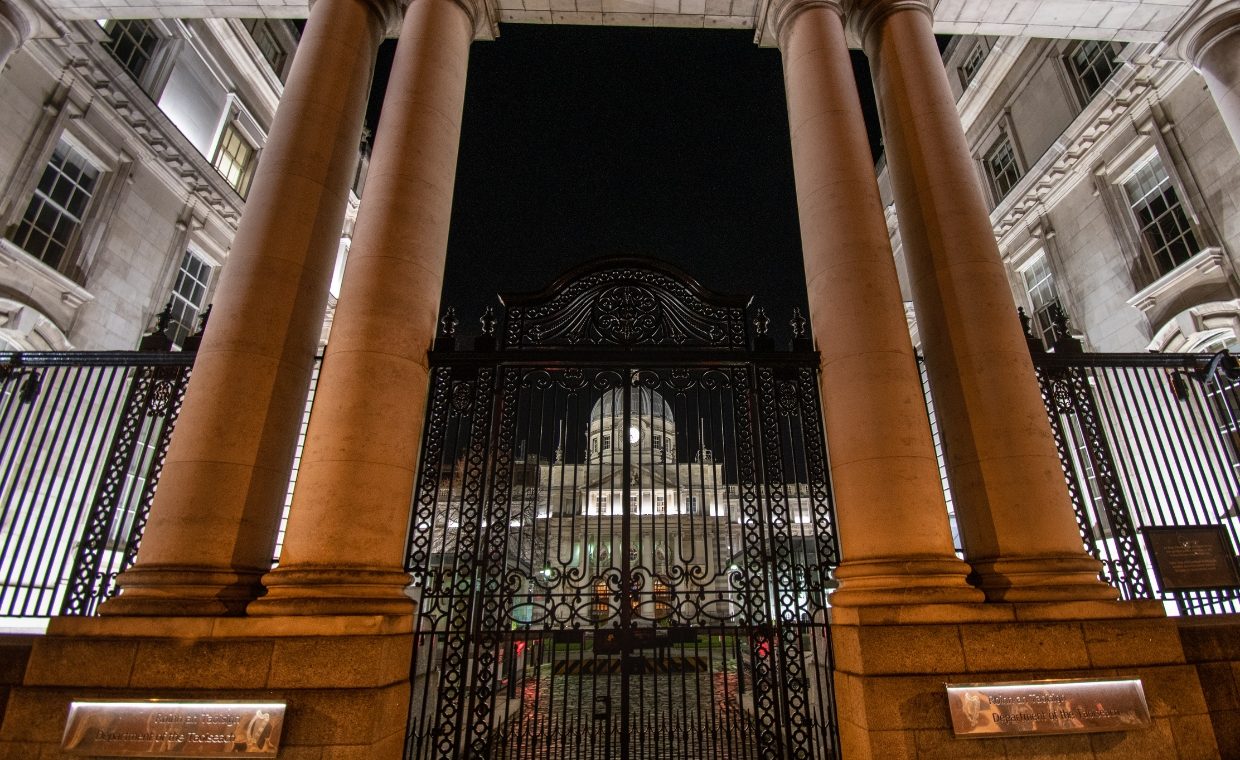 Brown pillared entrance in front of a domed a building at night