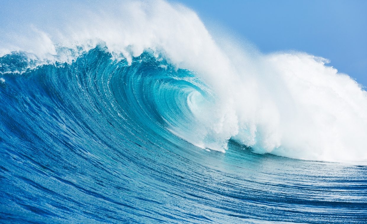 Large blue breaking wave with white foam on it