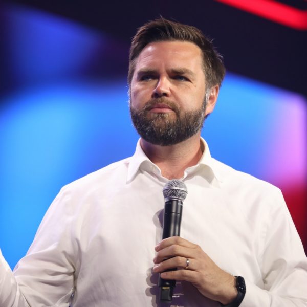 Bearded man holding a microphone in front of a blue background