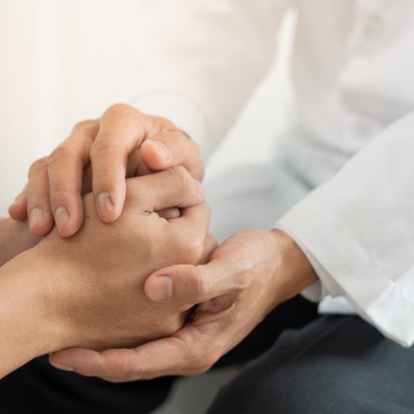 Man in a white coat holding another person's hands