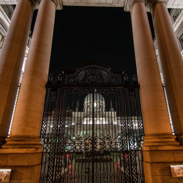 Brown pillared entrance in front of a domed a building at night