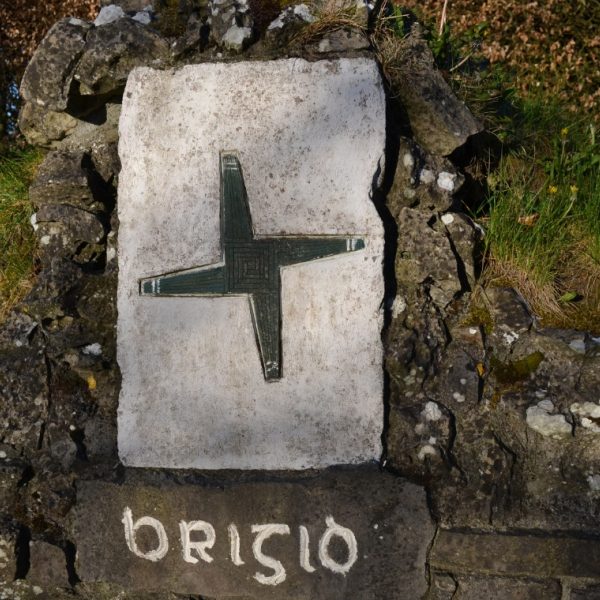 Brigid's Cross carved on stone above a well with words Brigid written under it