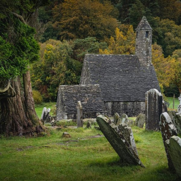 Small stone church with trees behind it and grave stones in front of it