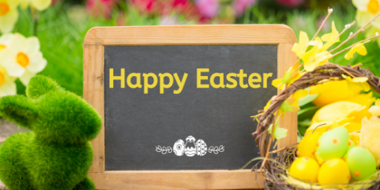 A sign on a small blackboard saying Happy Easter with a yellow easter basket in the foreground