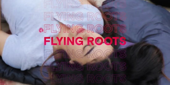 Still image taken from FLying Roots documentary. Shows one of the participants (Teenage girl) with eyes closed with Flying Roots in red in the foreground