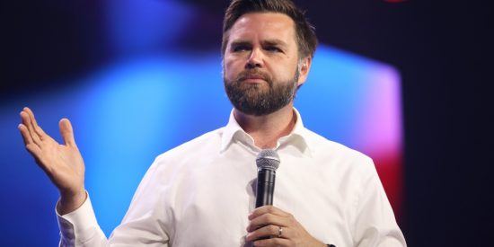 Bearded man holding a microphone in front of a blue background