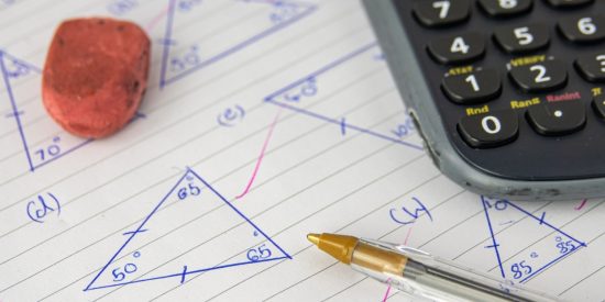 Lined piece of paper with triangles drawn on it and a red rubber, a biro and a calculator sitting on top of it