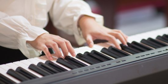 Person wearing a white sleeved shirt playing the piano