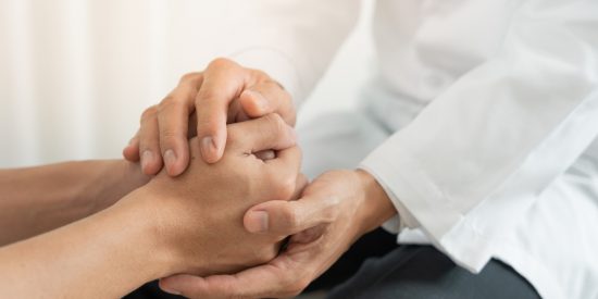 Man in a white coat holding another person's hands