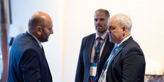 3 men in dark suits talking to each other