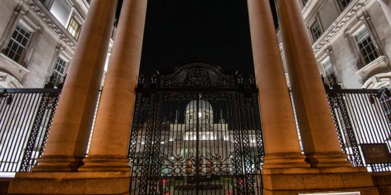 Brown pillared entrance in front of a domed a building at night