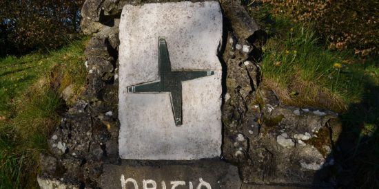 Brigid's Cross carved on stone above a well with words Brigid written under it