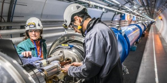 1 man and 1 woman in safety gear working on CERN's Hadron Collider