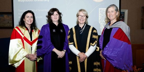 Four women in colourful robes standing in front of a screen