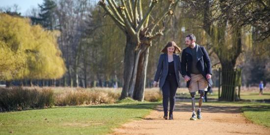 Photo of couple walking in the park, man uses prosthetic leg