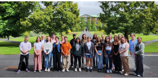 A group of people smiling at the camera with the Maynooth University South Campus in the background