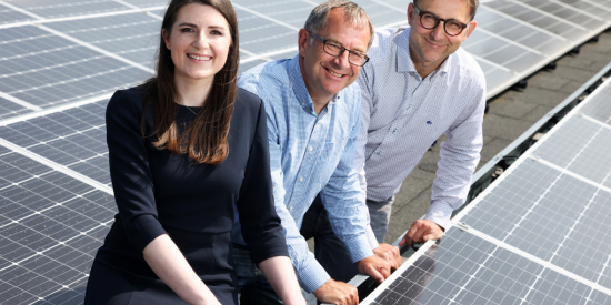 Three people sitting between solar energy panels