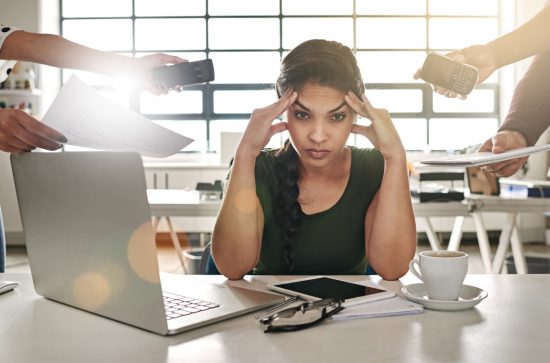 Woman at a desktop with a computer and tablet with four hands offering other digital devices