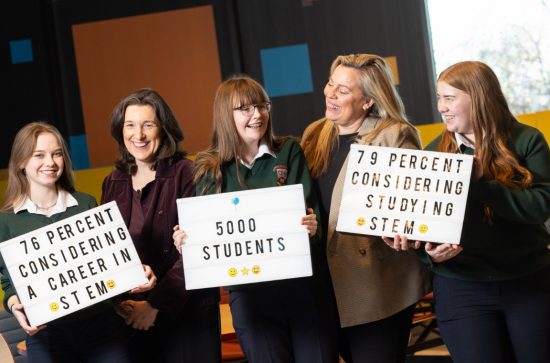 3 young girls in school uniform, and 2 mature women smiling, and holding signs that state '76 percent considering a career in stem', '5000 students' and '79 percent considering studying STEM' 