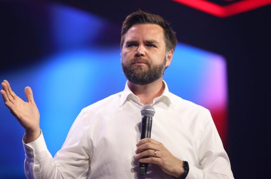 Bearded man holding a microphone in front of a blue background