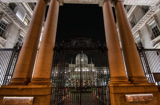 Brown pillared entrance in front of a domed a building at night