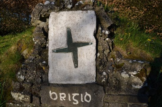 Brigid's Cross carved on stone above a well with words Brigid written under it