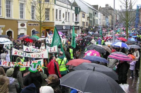 Street with Patrick's Day marchers and observers with umbrellas