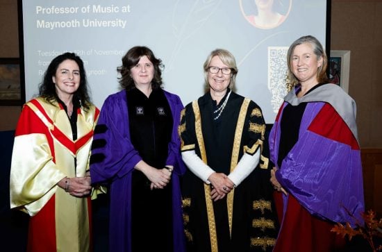 Four women in colourful robes standing in front of a screen